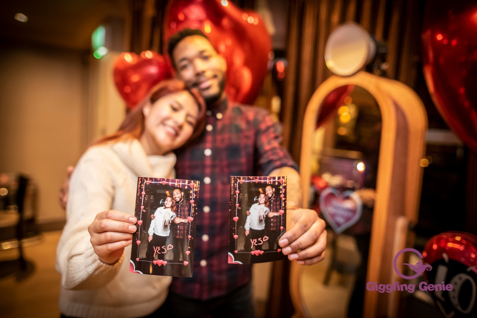 Couple enjoying photo booth prints at a birthday or celebration party in Surrey
